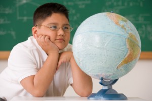 middle school boy looking at a globe